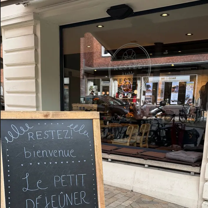 Kreidetafel „Restez! bienvenue – Le petit déjeuner“ vor dem Schaufenster