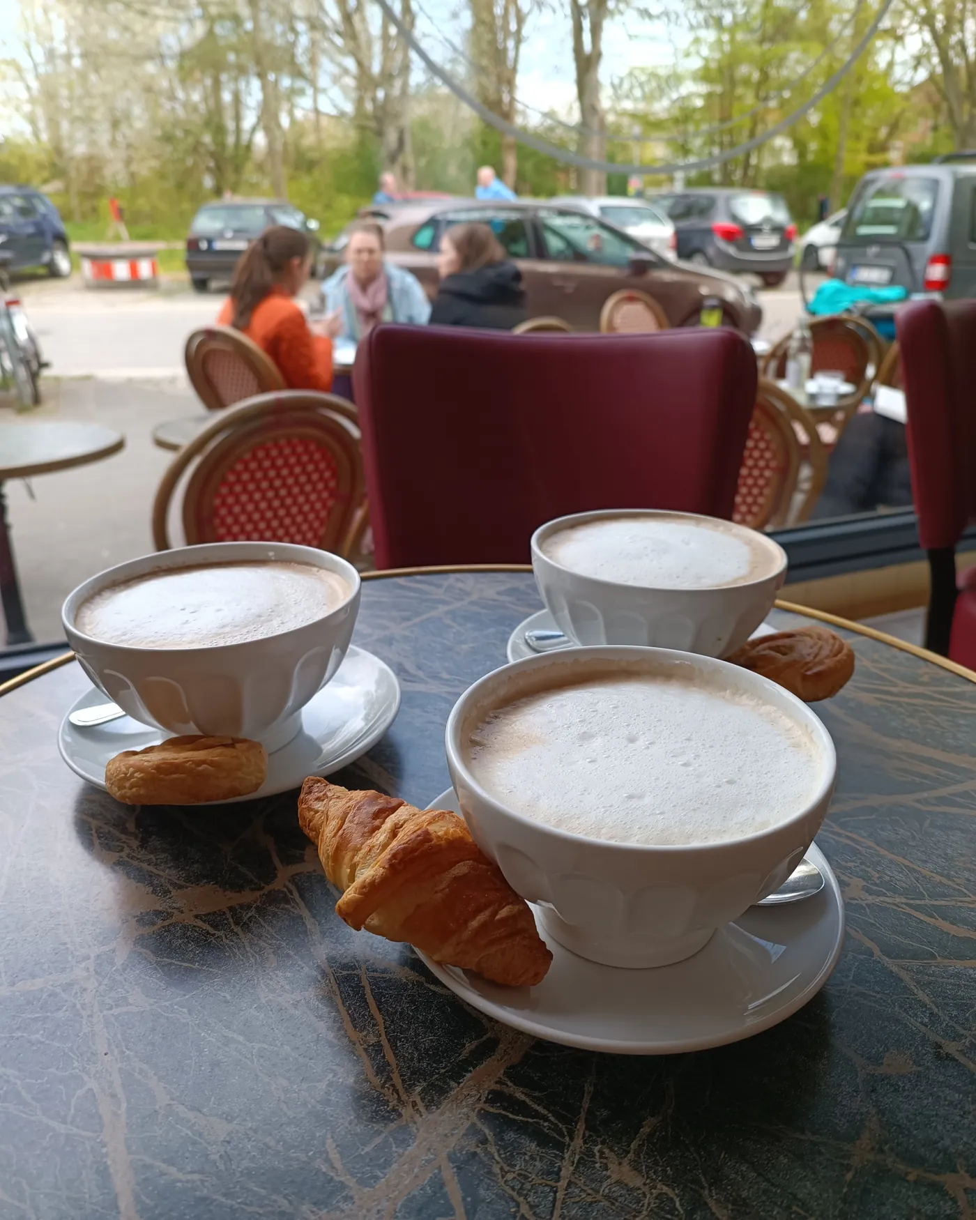 Milchkaffee und Croissants auf einem Tisch draußen vor dem Laden
